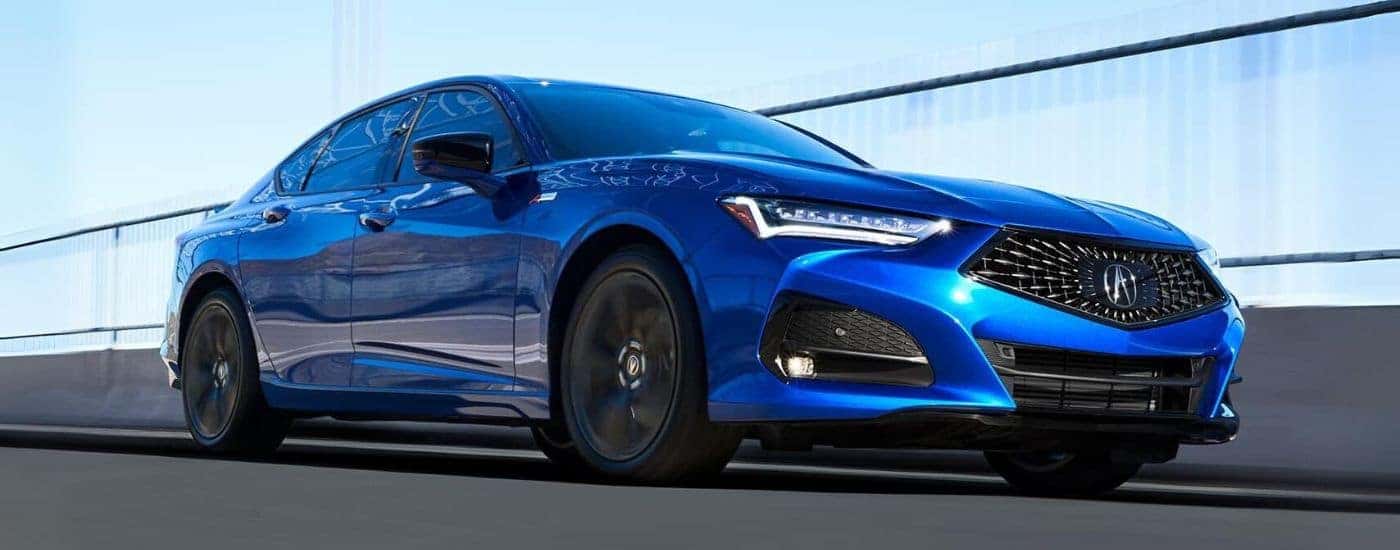 Blue 2023 Acura TLX driving on an empty road