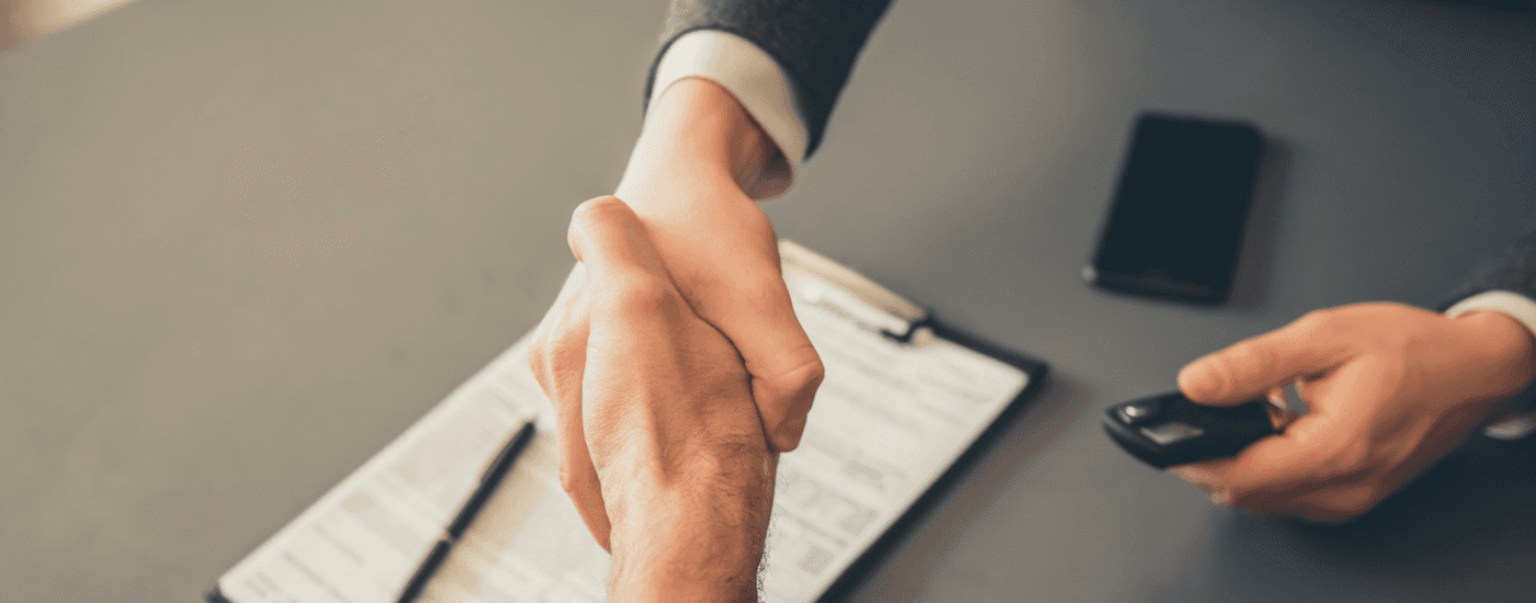 Two people shake hands after the sale of a budget used car near Durham
