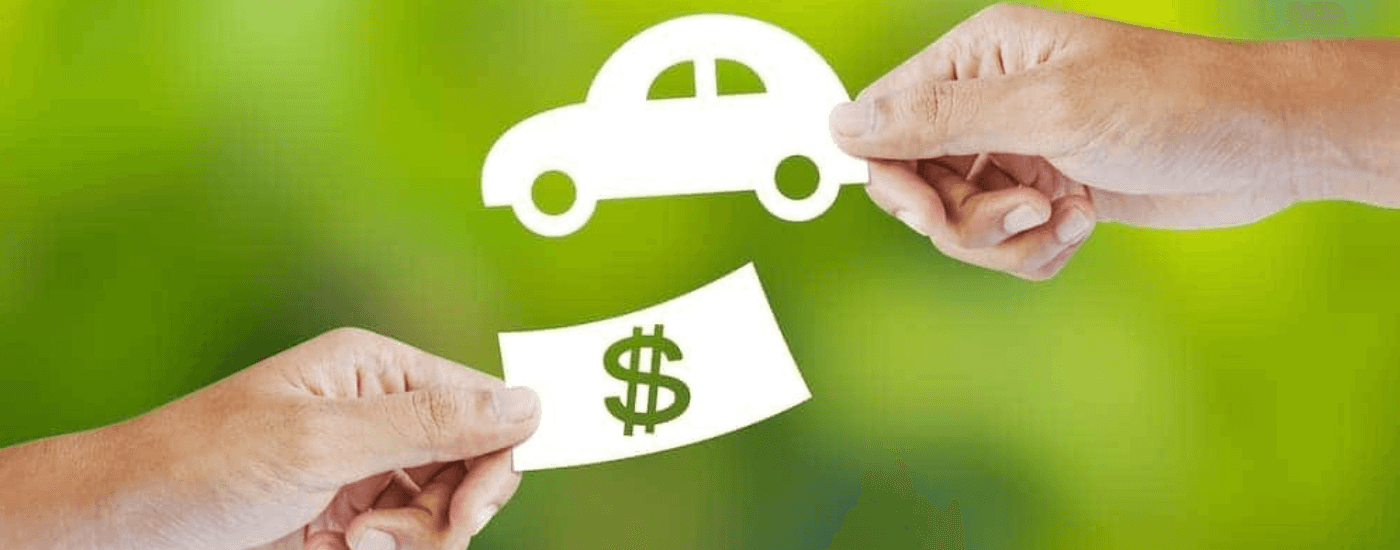 Hands are exchanging cut out cars for cash.