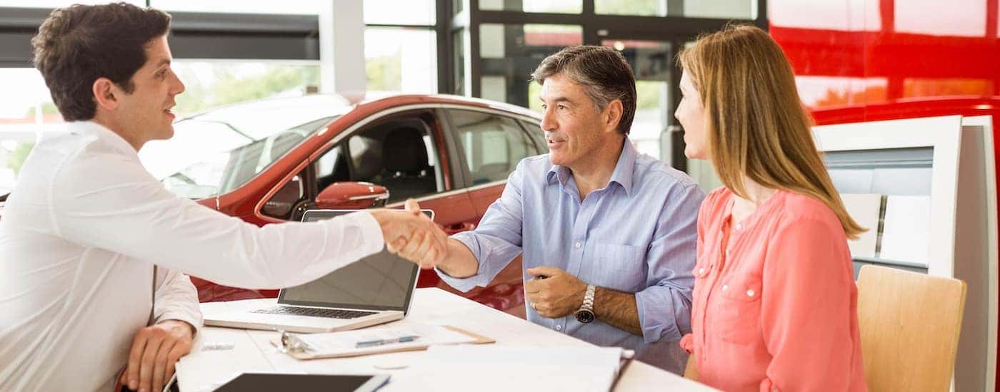 A couple talk with a salesperson about the selection of used cars near Durham, NC
