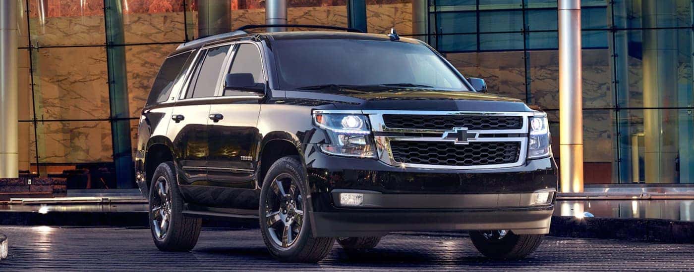A black 2017 Chevy Tahoe is parked in front of a glass building after leaving a used car dealer in Durham.