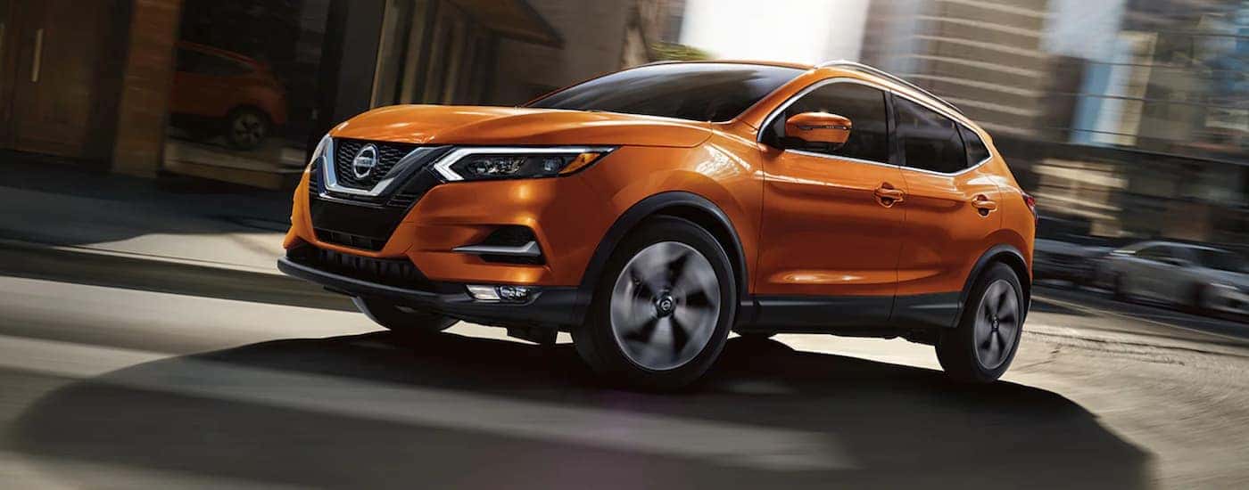 One of many popular used SUVs for sale, an orange 2020 Nissan Rogue, is shown parked.