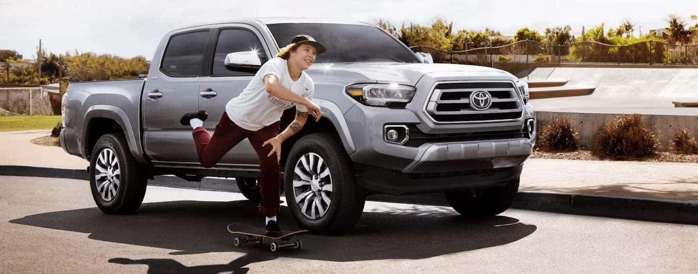 A person riding a skateboard by a white 2022 Toyota Tacoma Limited.