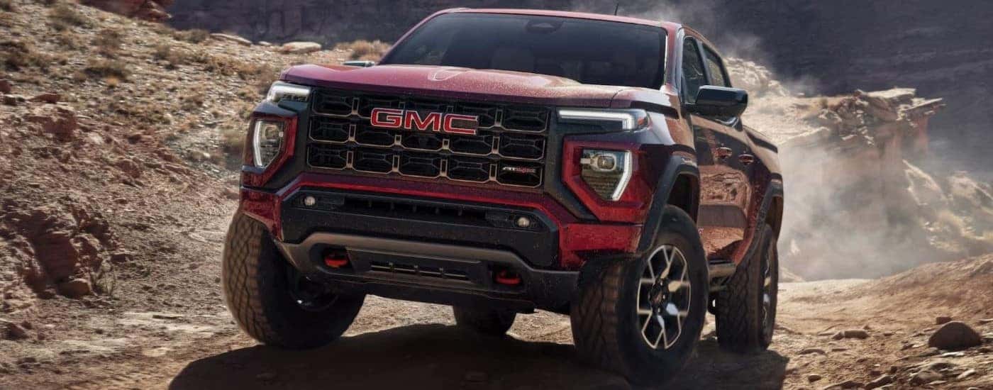 A red 2023 GMC Canyon AT4X driving off-road on a trail.