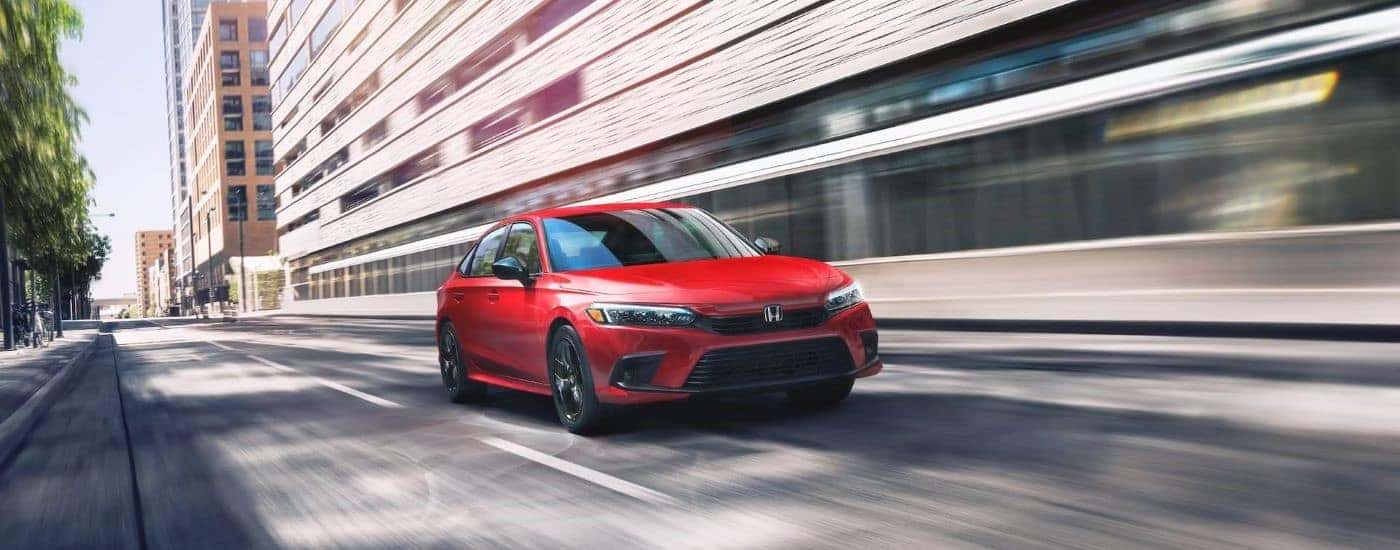 A red 2023 Honda Civic Touring is shown driving to view used cars for sale near Durham.