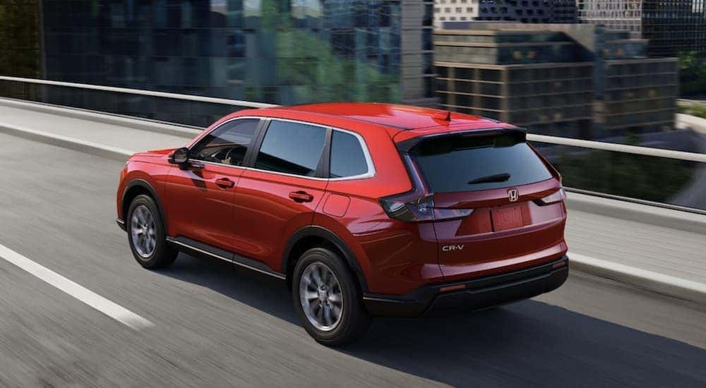 A red 2023 Honda CR-V driving on a bridge.