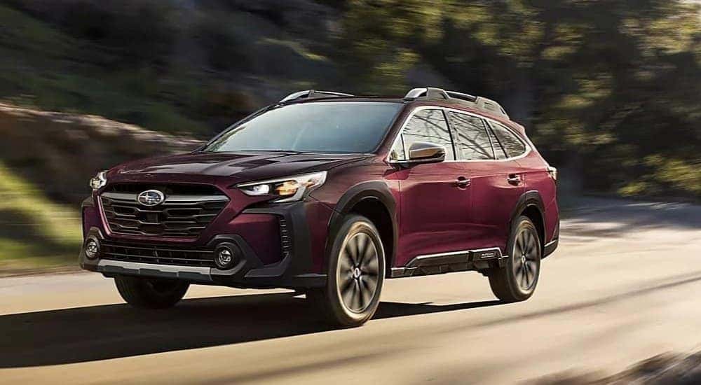 A purple 2023 Subaru Outback driving on a highway.