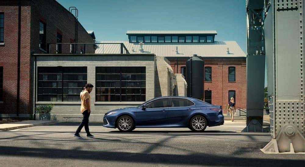 A blue 2024 Toyota Camry parked in a city.