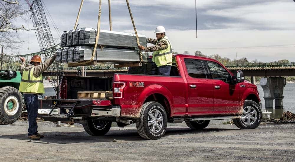 Building materials being loaded into the bed of a red 2020 Ford F-150.