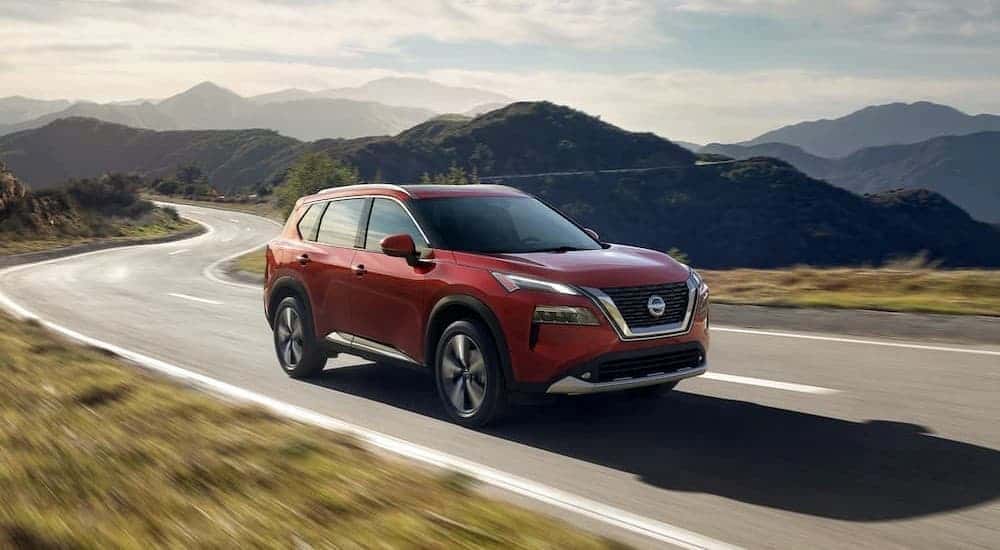 A red 2023 Nisan Rogue driving on a highway.