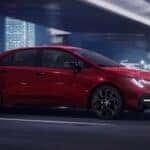 A red 2022 Toyota Corolla driving in a city.