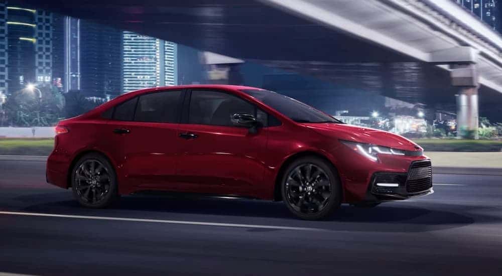 A red 2022 Toyota Corolla driving in a city.