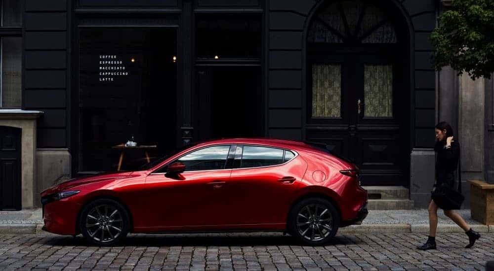 A red 2023 Mazda3 parked in a city.