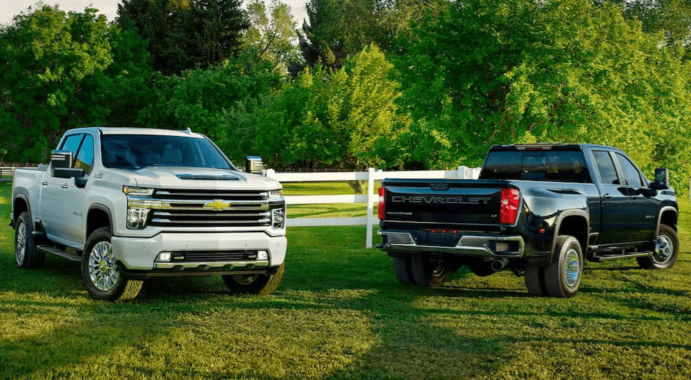 White 2020 Chevy Silverado 3500 HD parked next to a black 2020 Chevy Silverado 4500 on a field