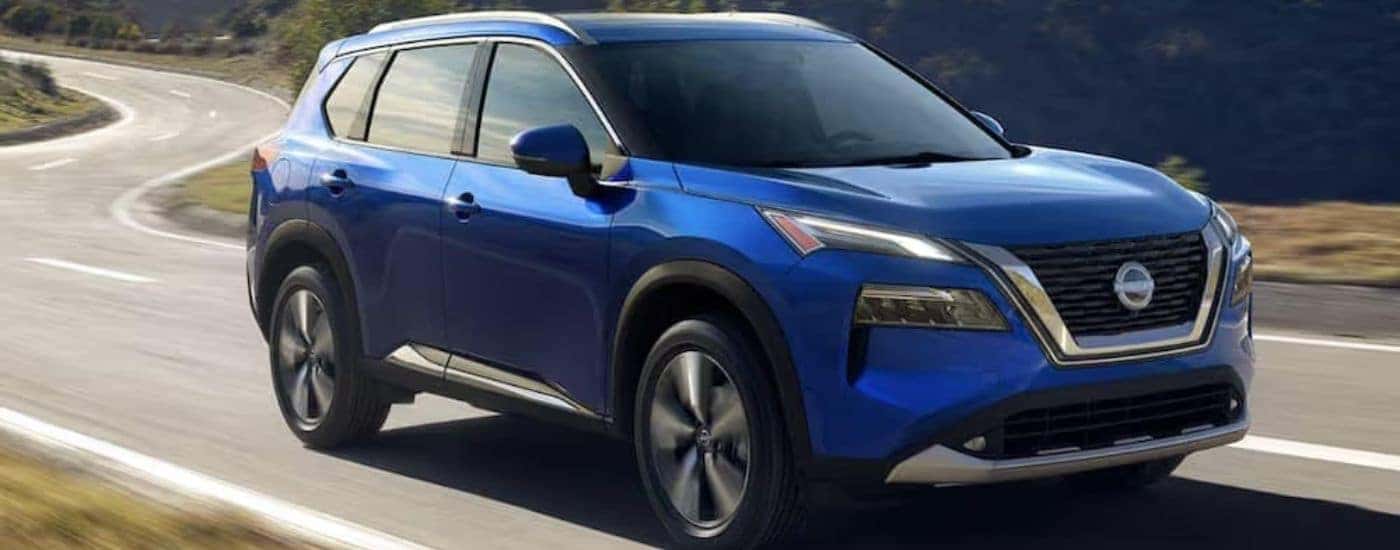 A blue 2022 Nissan Rogue is shown from the front driving on an open road.