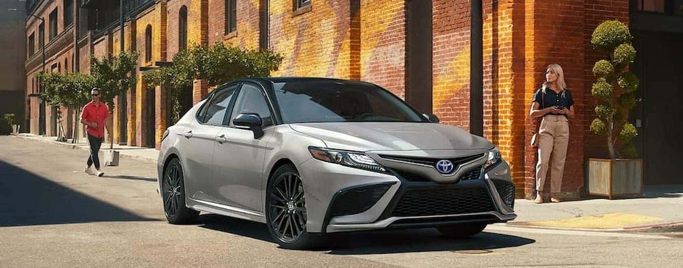 A silver 2023 Toyota Camry driving in a city.