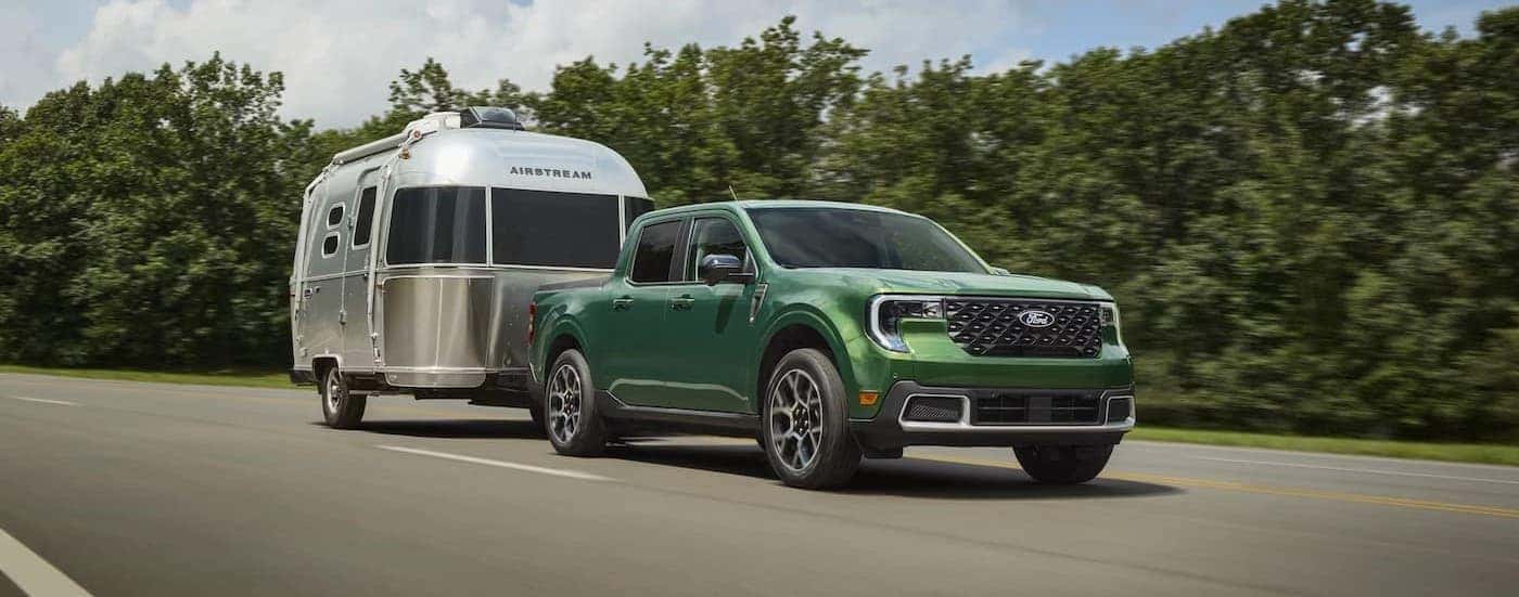 A green 2025 Ford Maverick towing a trailer.