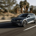 2025 Hyundai IONIQ 5 driving on a palm-lined road with desert mountains in the background.