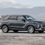 2025 Hyundai Palisade driving on a desert highway with mountains in the background.