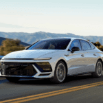 White 2025 Hyundai Sonata cruising through a mountain highway with guardrails