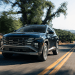 Black 2025 Hyundai Tucson Hybrid driving downhill through a forested road in daylight