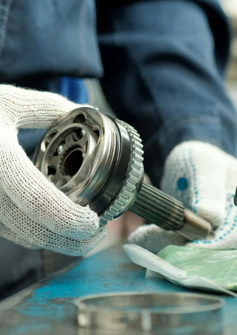 Mechanic inspecting CV joint axle shaft during automotive repair service
