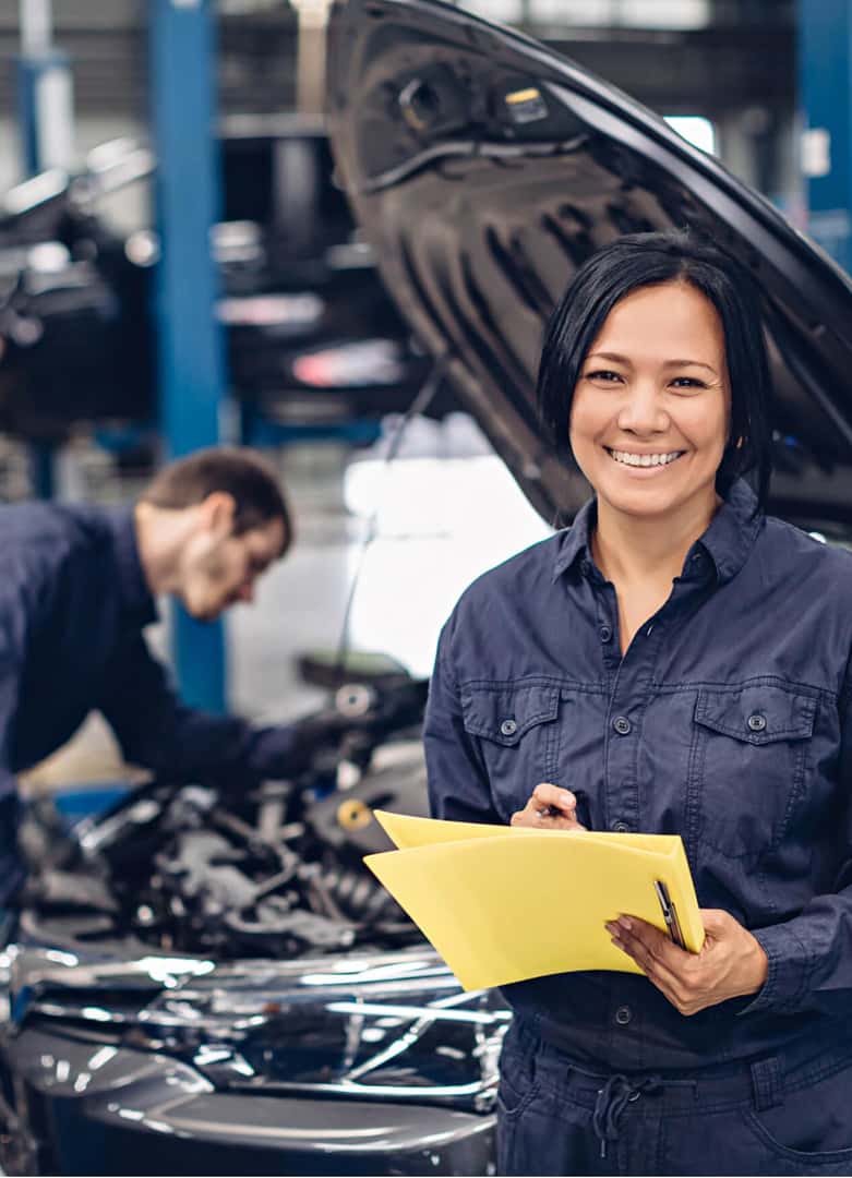 Female auto technician with clipboard conducting vehicle inspection at repair shop