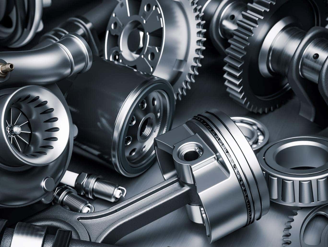 Close-up of various automotive engine components, including gears, a piston, bearings, spark plugs, and a turbocharger.