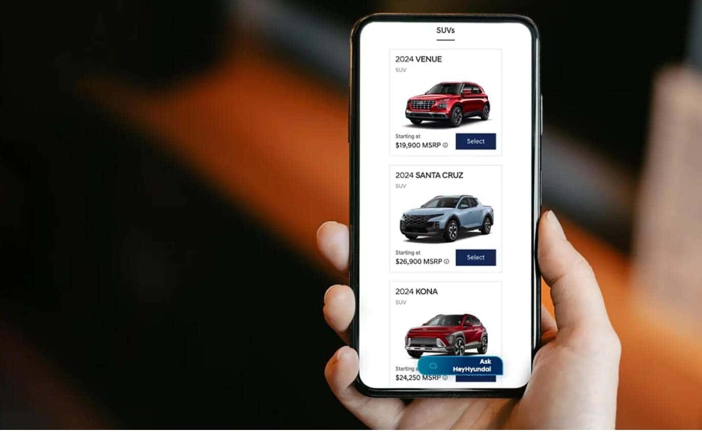 Close-up view of a hand holding a smartphone displaying the Hyundai digital vehicle lineup.