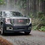 A grey 2020 GMC Yukon is driving on a forest road after leaving a GMC dealer near me in Indiana, PA.