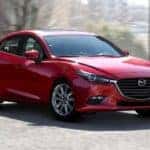 A red 2018 used Mazda 3 is driving around a corner near Indiana, PA.