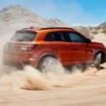 An orange 2020 Mitsubishi Outlander Sport is kicking up dirt in a desert.
