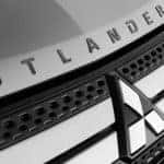 A closeup is shown of the grille badging on a silver 2020 Mitsubishi Outlander. Check with your Mitsubishi Dealer for info on the 2021.