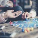 A group of housemates are playing a board game in their Pittsburgh, PA, home.