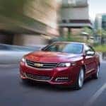 One of the popular used cars for sale in Indiana, PA, a red 2016 Chevy Impala is driving on a city street.