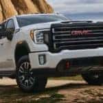 A white 2020 GMC Sierra 2500 is parked in front of a large desert rock.