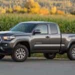 A grey 2016 Toyota Tacoma is parked in front of a corn field near Indiana, PA.
