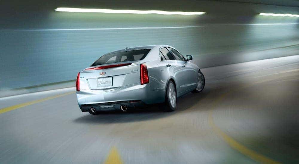 A popular used car, a silver 2018 Cadillac ATS, is driving in a parking garage.