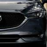 A closeup is shown of the grille of a grey 2020 Mazda CX-5 on a city street near Indiana, PA.