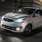 A silver 2017 Mitsubishi Mirage is driving on an Indiana, PA, street at night.