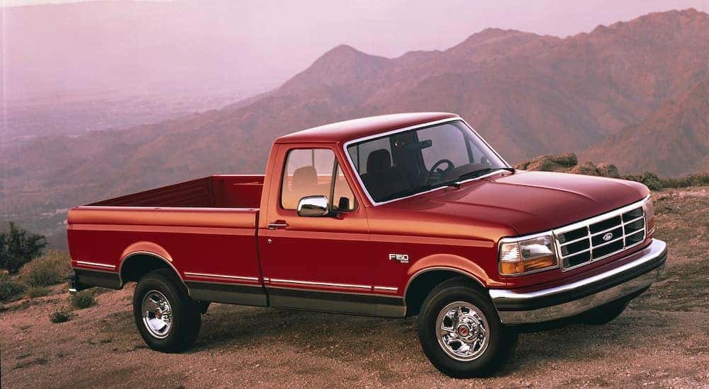 A red 1992 used Ford F-150 is parked with mountains in the background.