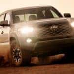 A grey 2021 Toyota Tacoma is off-roading in dirt after leaving a Toyota Truck dealer near me.