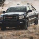 A black 2017 GMC Sierra 1500 is off-roading on a dirt trail.