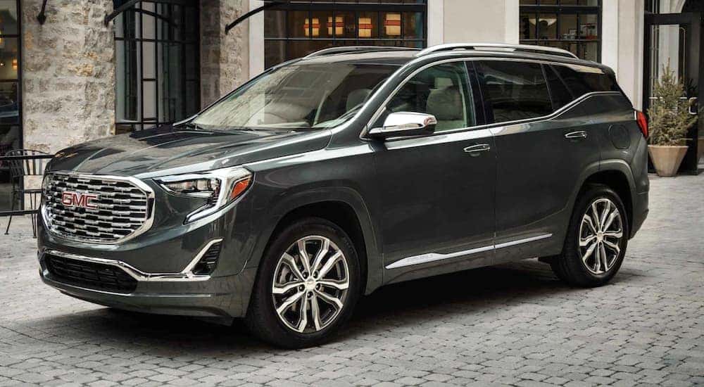 A grey 2021 GMC Terrain is parked in front of a stone building on a cobble street after leaving an Indiana, PA, GMC dealer.
