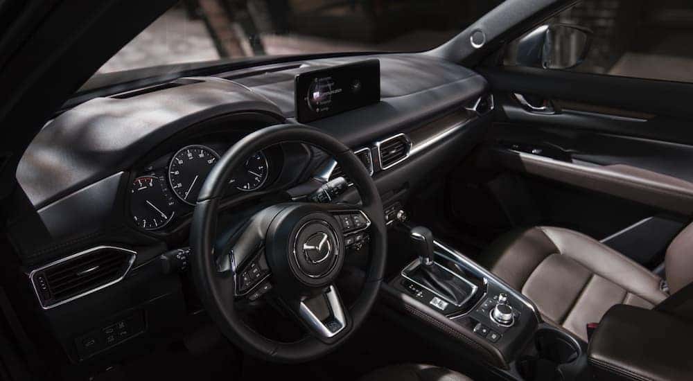 The wheel and dashboard are shown in a 2021 Mazda CX-5.