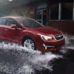 A red 2016 Subaru Impreza 2.0i Limited is shown splashing through a large puddle.