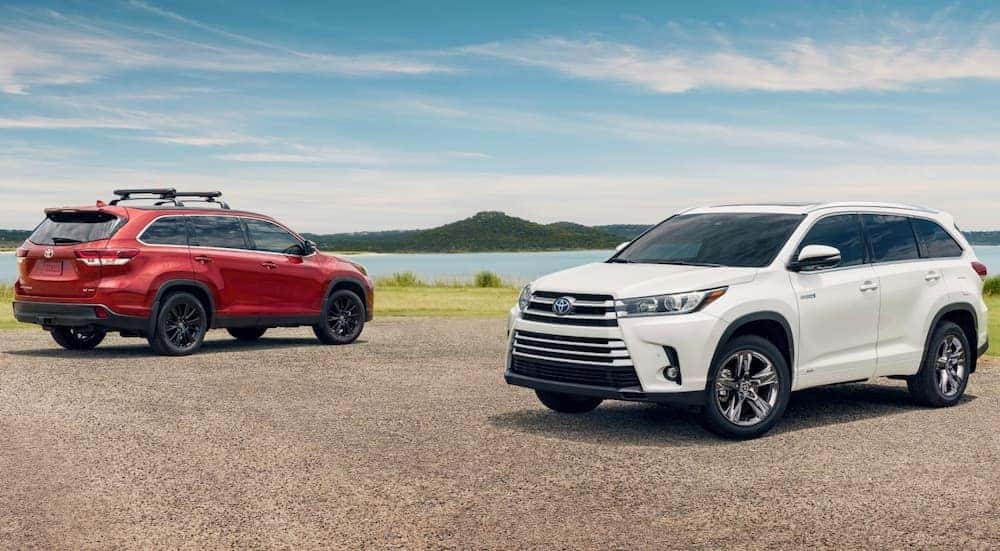 A red and white 2019 Toyota Highlander are parked in front of a lake.