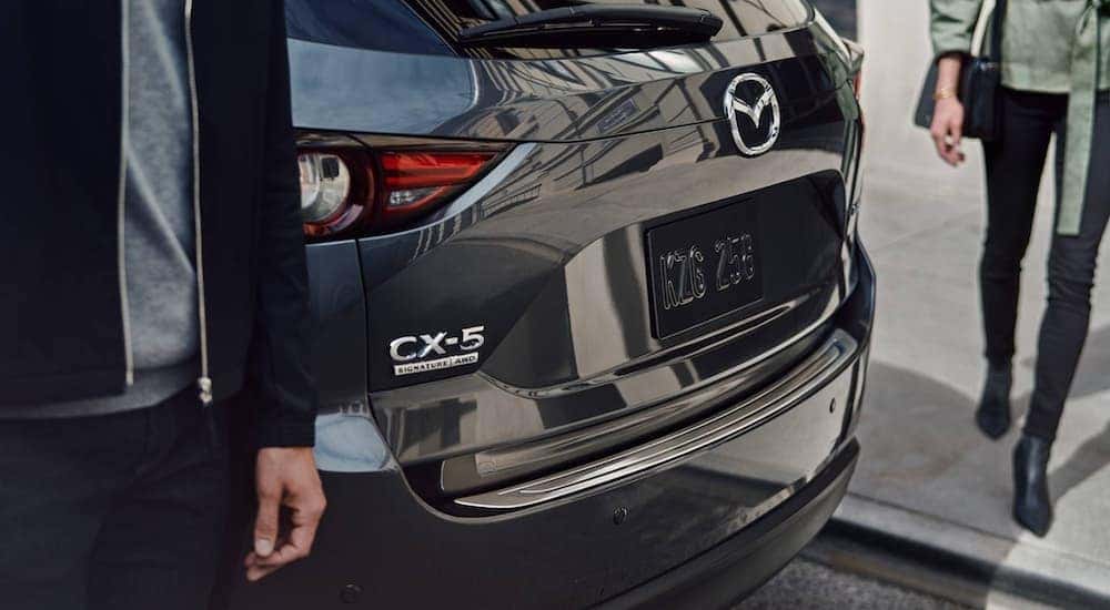 The rear of a black 2021 Mazda CX-5 is shown parked after leaving a used Mazda dealership.