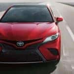 A red 2018 Toyota Camry is shown from the front driving down a road after visiting a used car dealer near you.