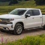 A white 2020 Chevy Silverado 1500 High Country is shown on a country road after visiting used truck dealers near you.